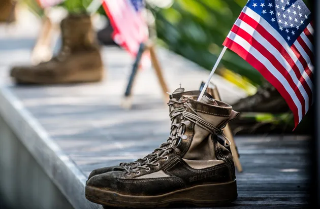 Military combat boots and an American flag, symbolizing support for veterans through Palmetto Warrior Connection (PWC).