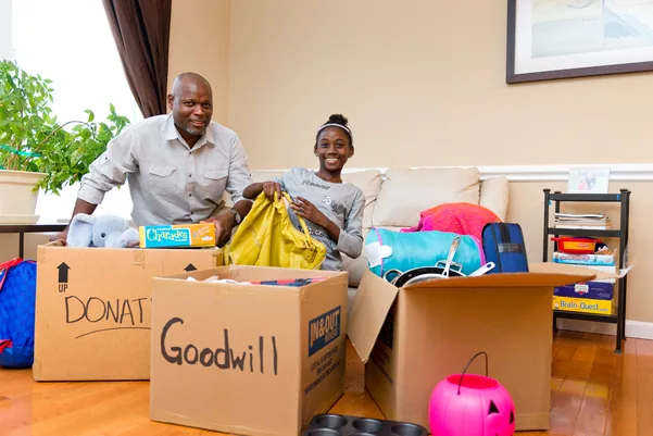 African American father and daughter placing donating material goods into Goodwill boxes to be donated