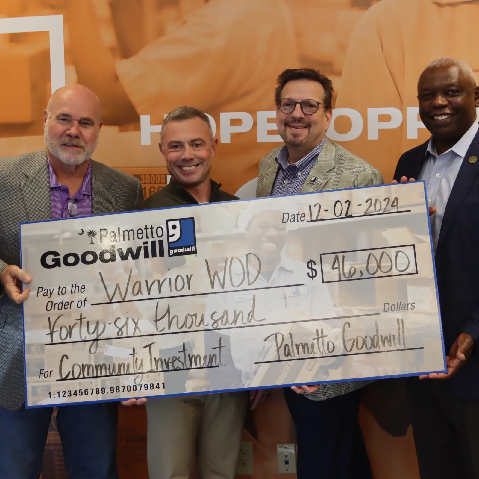 Group photo of a $46,000 community investment check presentation from Palmetto Goodwill to Warrior WOD, supporting veterans with PTSD.