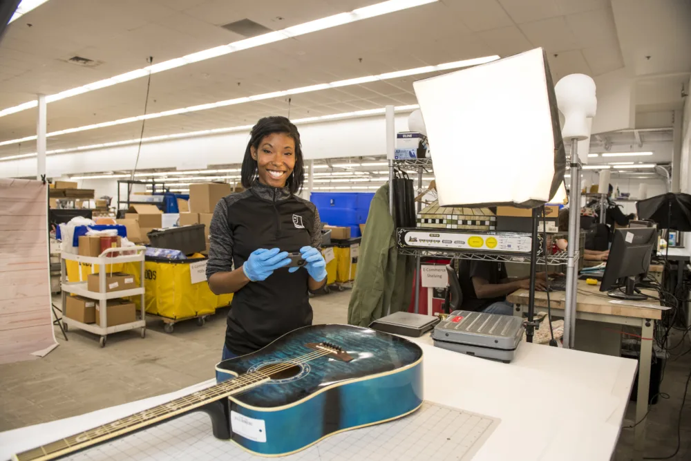 Palmetto Goodwill employee taking photos of a donated guitar.