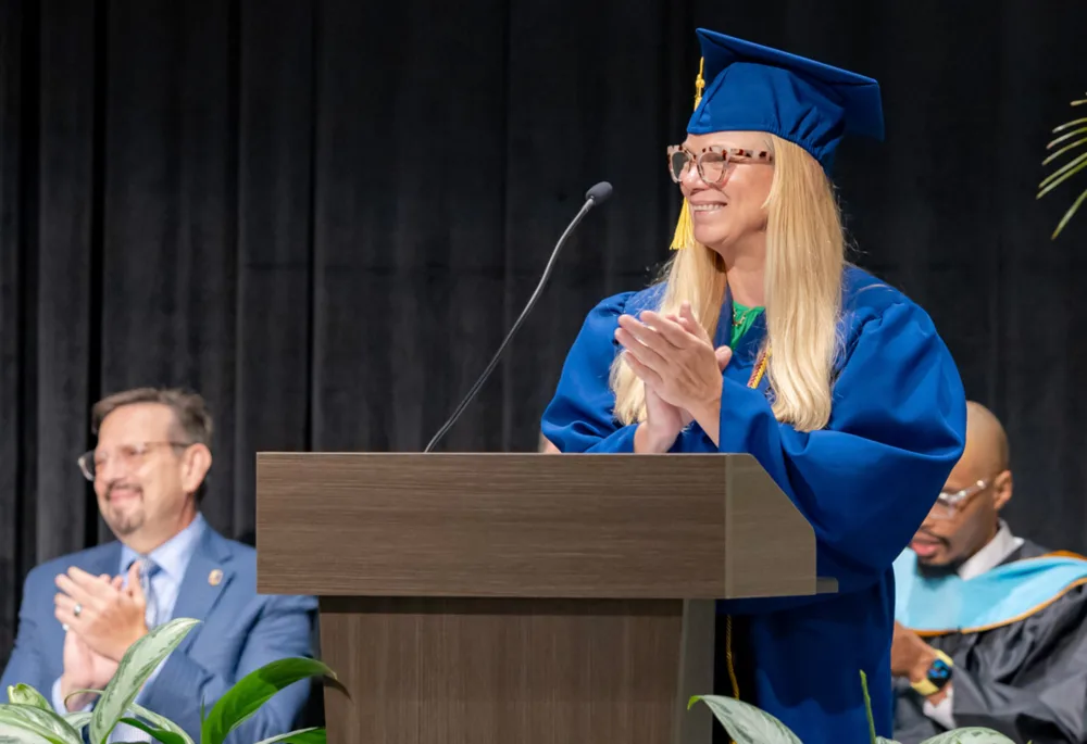 Palmetto Excel Center adult valedictorian receiving applause at graduation, alongside Brian Itzkowitz, President and CEO of Palmetto Goodwill.