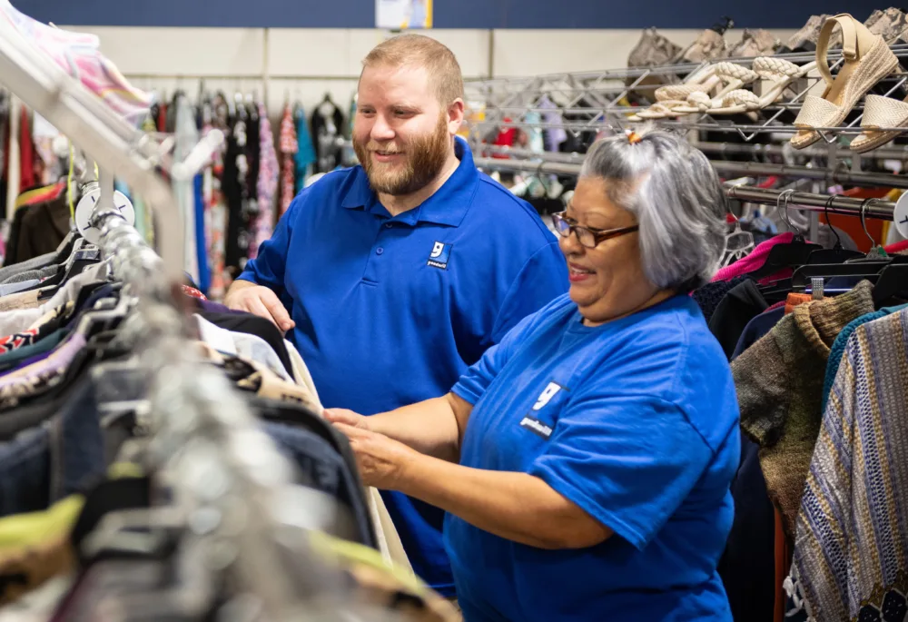 Mature Palmetto Goodwill employee collaborating with a co-worker in a retail store, representing the pathways opened by goodwill job connection near me.