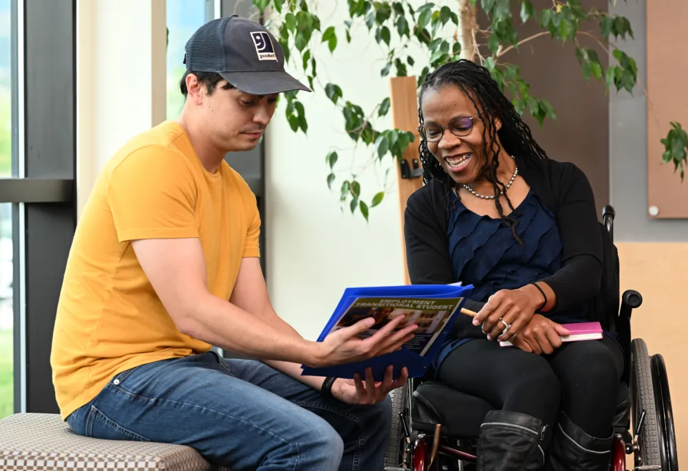 Palmetto Goodwill job coach assisting a woman in a wheelchair with her career documentation, illustrating the commitment to reasonable accommodation and support through the AbilityOne Program.