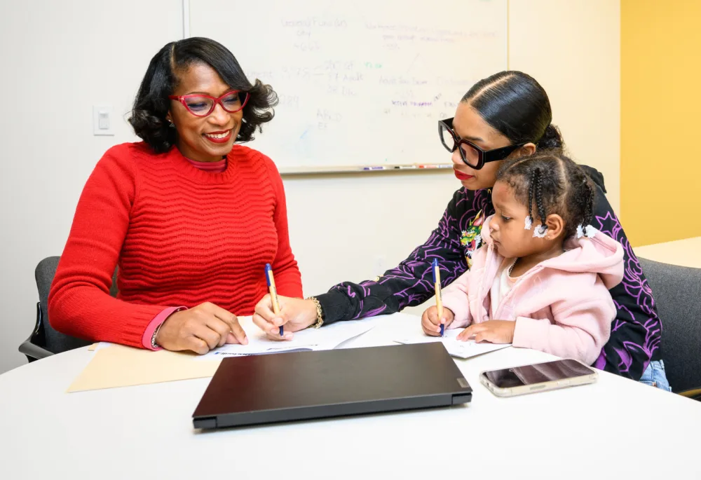 Palmetto Goodwill coach assisting a mother and child with job application or financial forms, emphasizing family support at the Career Opportunity Center.