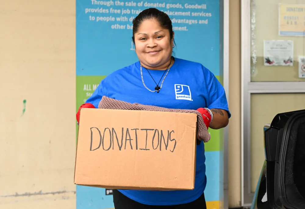 Palmetto Goodwill employee accepting a donation box, illustrating how goods donated and thrift shopping fund free digital skills training in South Carolina.