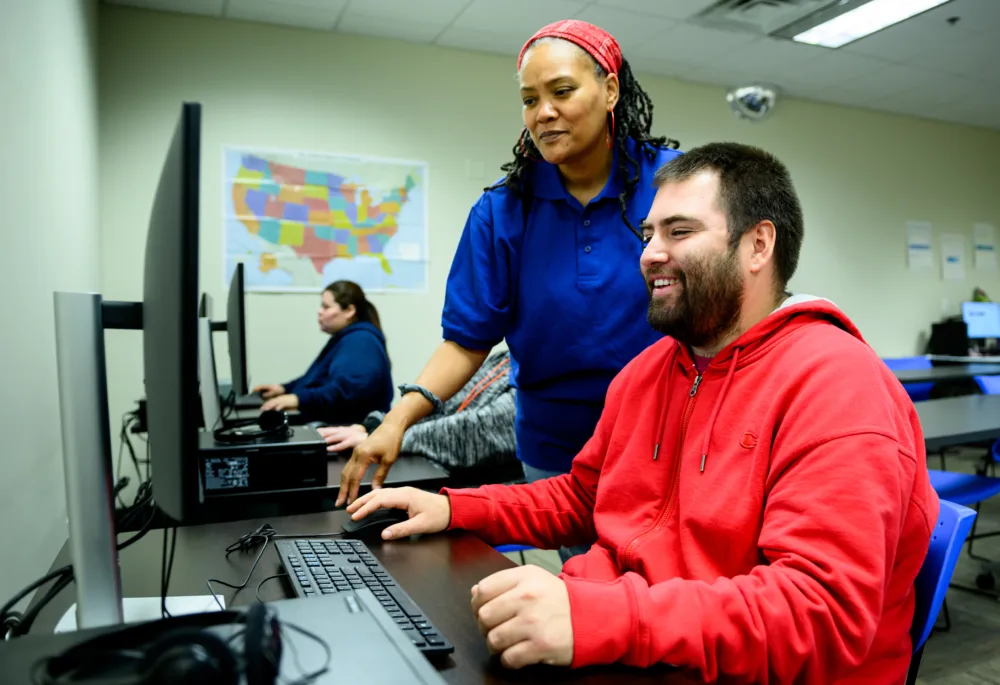 Palmetto Goodwill job coach assisting an Enclave member with computer training, supporting their digital literacy for SC disability employment.