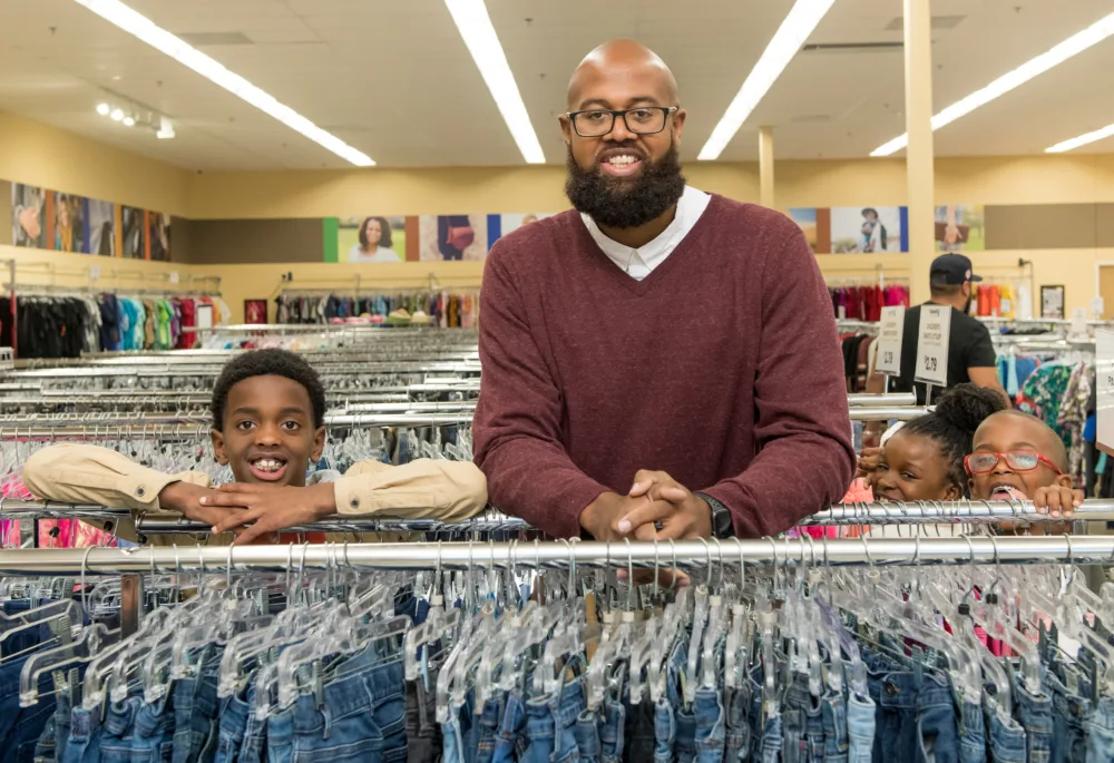 A father and children browsing a large selection of quality jeans at a Palmetto Goodwill retail location, highlighting the best thrift store SC residents can visit.