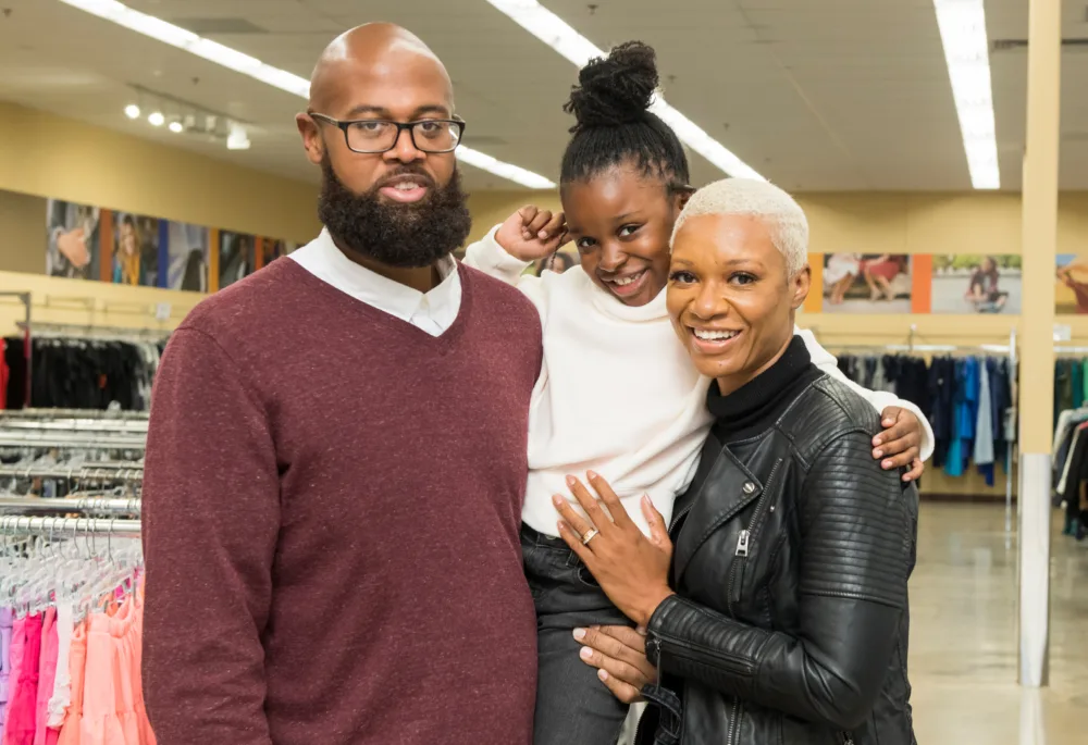Happy family of three posing in a retail aisle at Palmetto Goodwill, demonstrating why it is the best thrift store near me for quality finds and community impact.