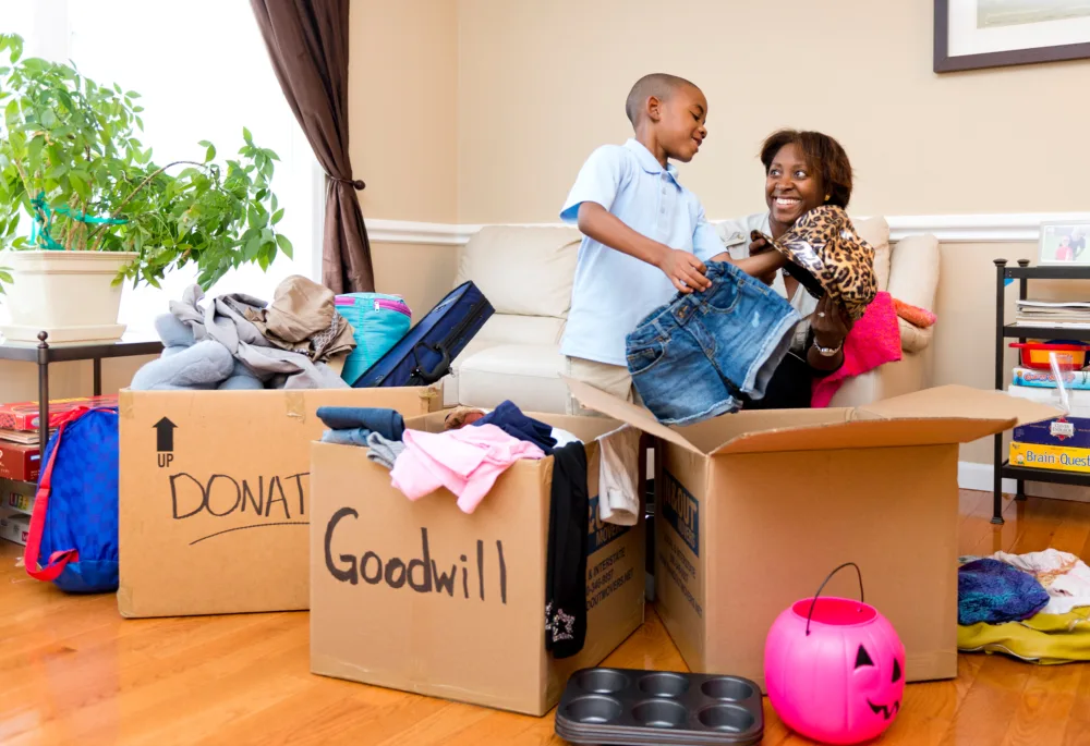 A mother and son packing a Goodwill donation box while decluttering their home to support local job training in South Carolina.