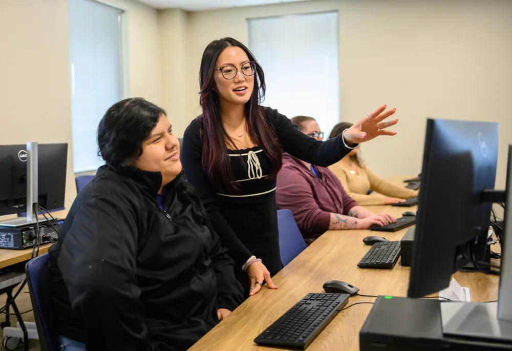 An instructor helps a student develop new computer skills while receiving free resume help SC in a Palmetto Goodwill training lab.