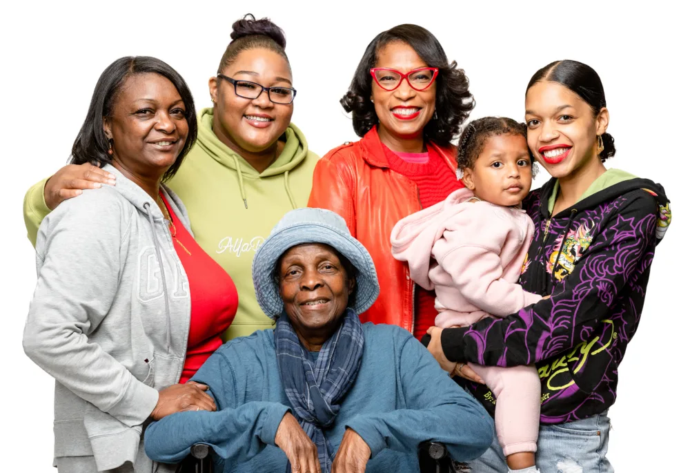 A diverse, multi-generational group of smiling women and a young child, representing the South Carolina families who benefit from Palmetto Goodwill's mission and career services.