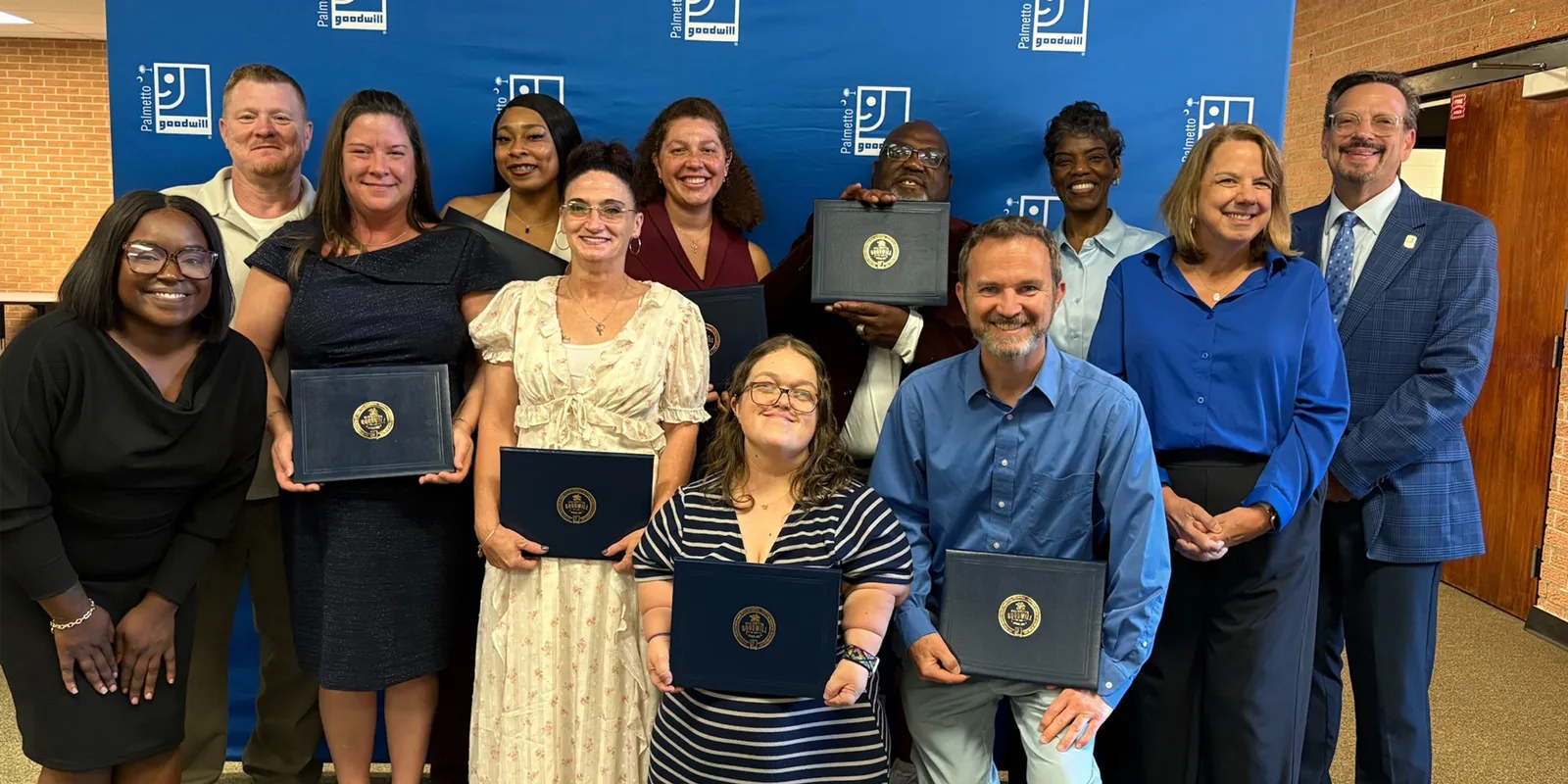 A group of smiling people posing with their graduate certificates.